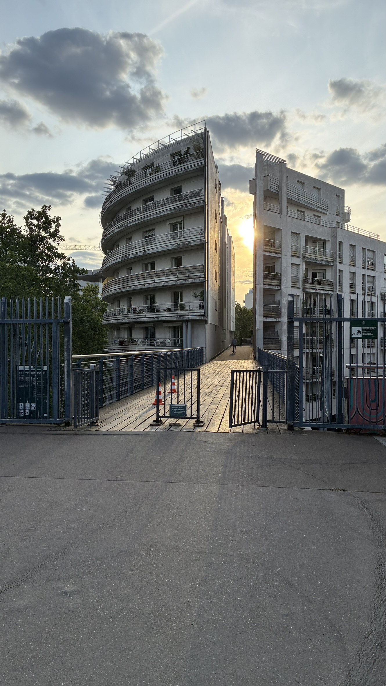 Modern buildings framing the sun along a walkway in Paris